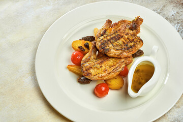 Grilled baked chicken with vegetables and sauce in a white plate on a white tablecloth. Coq au vin
