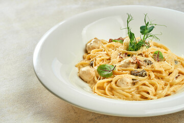 Linguini pasta in cheese sauce with chicken meatballs in a white plate on a white tablecloth
