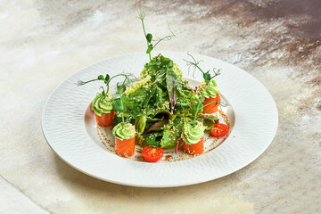 Salmon salad with avocado mousse in a white plate