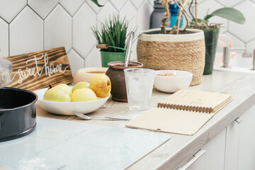 Cooking of apple pie in kitchen. Table with ingredients, cooking utensils and recipe book