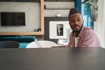 Fototapeta premium Tranquil African American male freelancer sitting at laptop