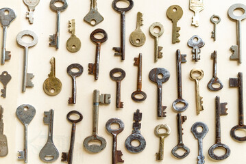 Obraz premium Antique keys are commonly reffered to as a bit or barrel keys, the former having a solid shrank and the latter being hollow. Here are some old antique and vintage keys against paper background.