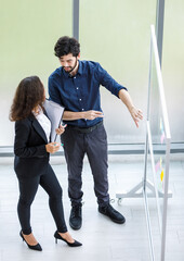 African American businesswoman trainee in formal suit standing and discuss with Caucasian bearded professional businessman trainer in meeting room