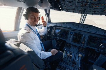 Male plane captain giving two-finger salute to camera