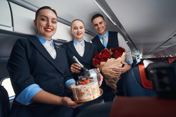 Joyful cabin attendants smiling at camera with presents