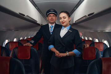 Satisfied flight attendant and pilot standing near passenger seats © Viacheslav Yakobchuk