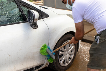 the man who washes the white car himself, is foaming it with a brush.