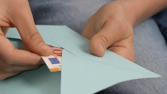 Teenage boyd hands open blue envelope, checking, counting a few cash Euro banknotes. Present gift, saving, financial literacy for children