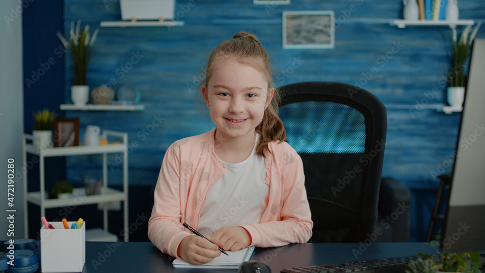 Poster portrait of child doing homework on notebook for education at desk with computer. little girl using 