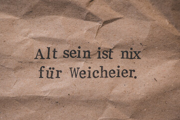 Gestempelter Text auf zerknittertem Papier. Alt sein ist nix für Weicheier.