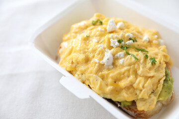 Avocado and scrambled eggs toast with delivery package in white background