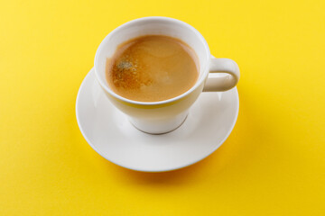 Black coffee in a cup on a yellow background