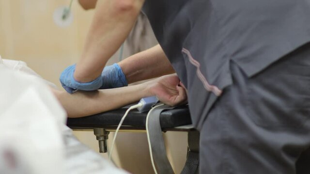 doctor anesthesiologist puts a catheter and injects anesthesia into a vein of the patient's arm, surgery.