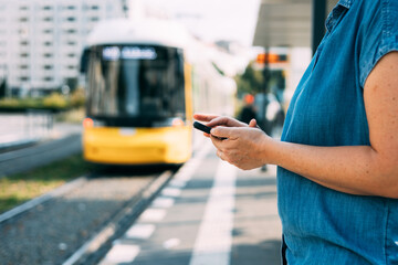 Woman interacting with the smart phone on the tram station