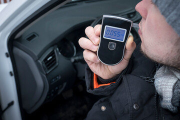 a man with a breathalyzer in the car, testing for alcohol and drug intoxication of the driver,...