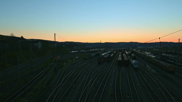 Dusk panorama of switch yard in Hagen Vorhalle, Germany. multiple freight trains and waggons are standing on the rails. Locomotive driving by on the left side.