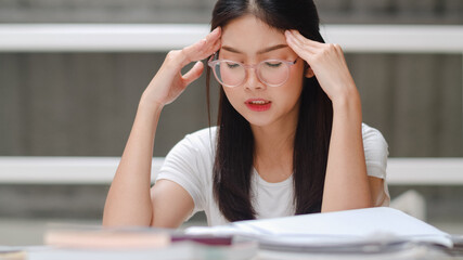 Asian student women read books in library at university. Young undergraduate girl stress tired have problem while study hard for knowledge on lecture desk at college campus concept.