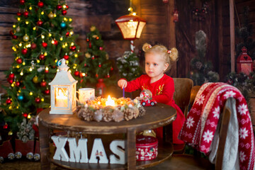 Cute little blond child, curly girl with two ponytails, sitting on a table with christmas...