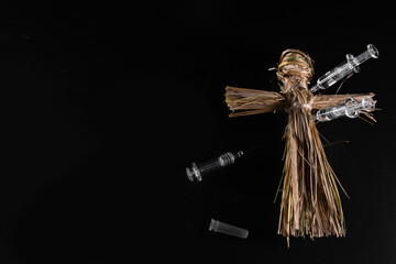 Voodoo doll and syringes on a black background. People management concept. Compulsory vaccination....