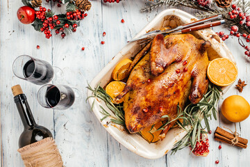 Traditional roasted stuffed Christmas Peking duck with rosemary and oranges on wooden background....