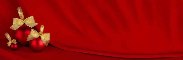 Christmas banner in rich luxury style -  shiny red balls, gold ribbon on scarlet silk curtain with smooth creases, copy space. New year background for design of website, header.