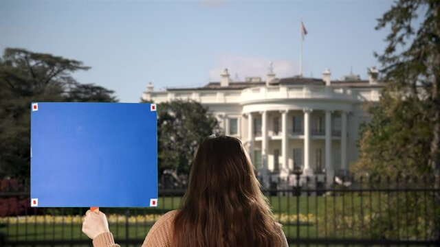 Woman holds a blank green screen chroma key sign for protest outside White House in Washington, DC. Tracking points for custom sign message. 