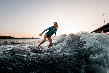 Fototapeta premium beautiful woman wakesurfer riding down the splashing wave on warm day
