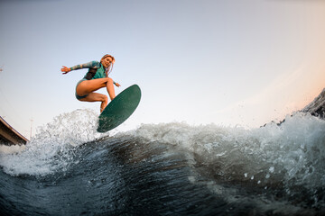 energy woman wakesurfer skilfully jumping on wakesurf down the river wave
