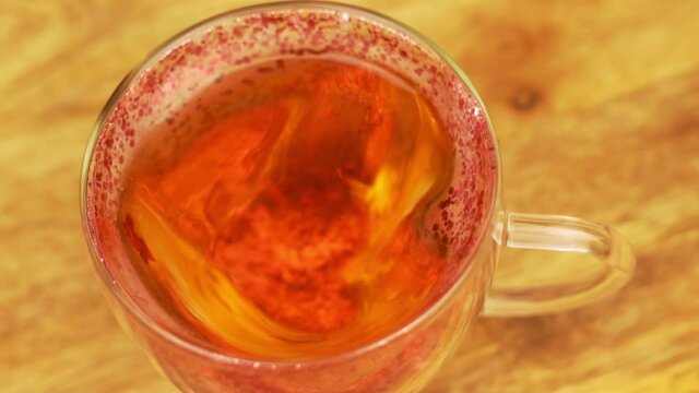 Natural Tea in Transparent Heart Shaped Cup with Red Sequins, Close-up, Isolated. Tea for Beloved, Romance, Love. Healthy Breakfast.