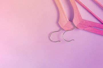 Two wooden hangers on a purple pink background lying upside down. Flat layout, copy space, horizontal background. Clothes hangers, shopping concept, sales