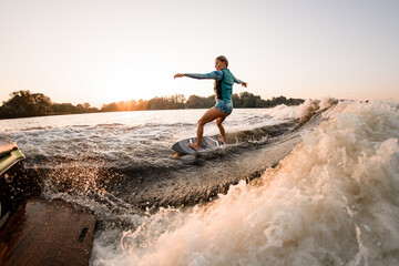 wet woman masterfully riding wakesurf on splashing river water. Active water sports