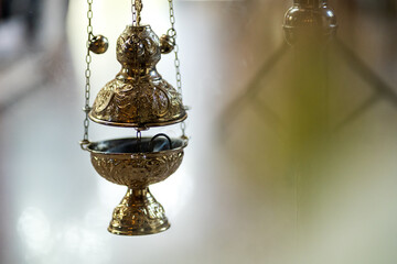 Close-up with a golden censer in which incense burns and smokes against a bright background with pleasant bokeh, traditions and holidays in the Orthodox Christian church, Lent and Advent. - Powered by Adobe