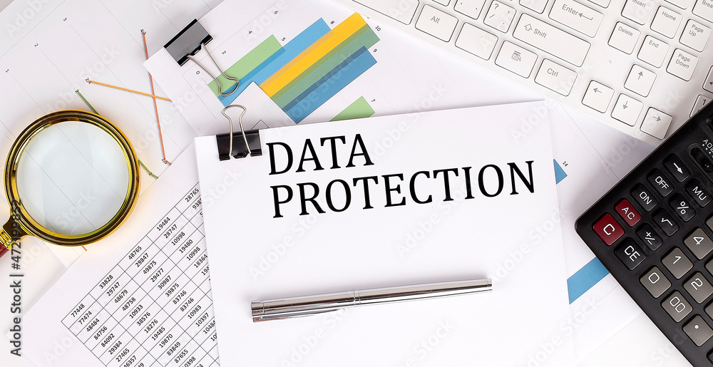 Poster data protection text on the white paper on the light background with charts paper ,keyboard and calc
