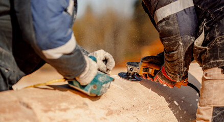 Industrial work carpenter grinds log with electric jointer, construction frame building site of house made of wood