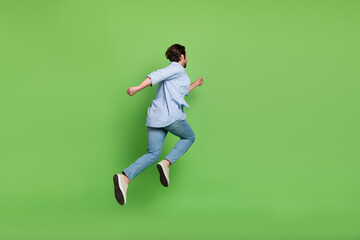 Fototapeta na wymiar Back rear view full size photo of young guy hurry run jump wear casual outfit isolated over green color background