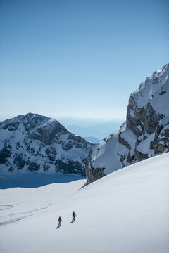 Junges Paar beim Schneeschuhwandern am Dachstein Gletscher in Österreich unter blauem Himmel