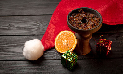 hookah bowl with tobacco with a Christmas red hat on a dark background. Christmas accessories