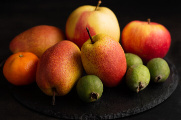 On a dark background, a blurred image of pears, feijoa, apples.