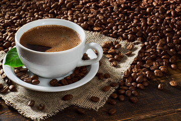 Cup of coffee and coffee beans on old wooden table