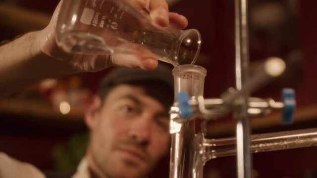 vintage chemist alchemist puring liquid into flask