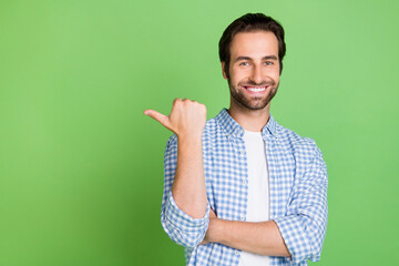 Photo of cute millennial guy indicate empty space wear checkered shirt isolated on green color background