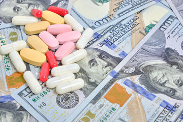 Pills are scattered on hundred dollar bills.Concept of expensive medicine.