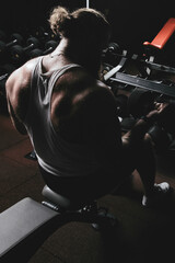 Muscular bearded man bodybuilder training in gym. Fit muscle guy workout with weights and dumbbell