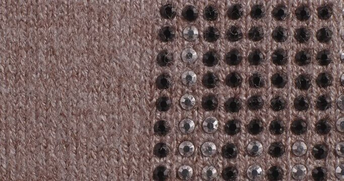 The texture of the knitted part is close-up. The fabric is decorated with rhinestones.