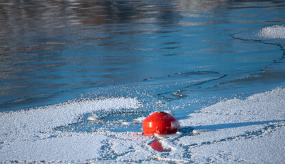 Bright red buoy floating alone in middle of ice and snow in the Baltic Sea in Helsinki, Finland just before complete freeze over of the sea on an extremely cold January afternoon on January 15, 2021.