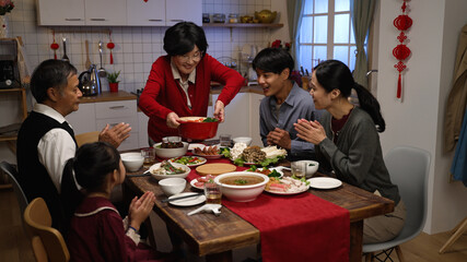 cheerful asian senior woman grandmother in red clothing putting thumb up while serving her specialty on table, feeling proud of her cooking. ready to have family reunion dinner on lunar new year - obrazy, fototapety, plakaty
