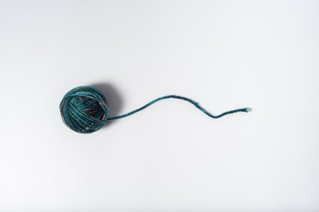 Dark blues multicolored ball of yarn with loose thread on white background