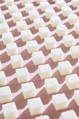 Refined sugar on pink background.Cubes of sweet and white sugar in geometricshape. Hard shadows.