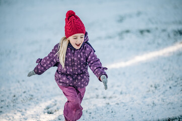Fototapeta na wymiar Children play outdoors in snow. Outdoor fun for family. Christmas vacation. Little girl running in winter