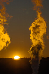 chimney smoke in front of the rising sun